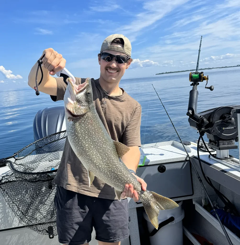 Customer holding lake trout caught on Lake Ontario fishing charter.